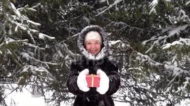 幸<strong>福</strong>微笑的女人<strong>送红色</strong>的礼物盒，站在白雪皑皑的公园里